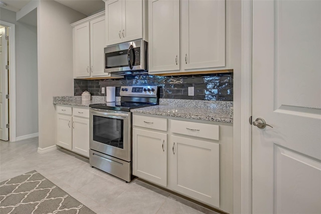 kitchen featuring light stone countertops, appliances with stainless steel finishes, tasteful backsplash, light tile patterned floors, and white cabinets