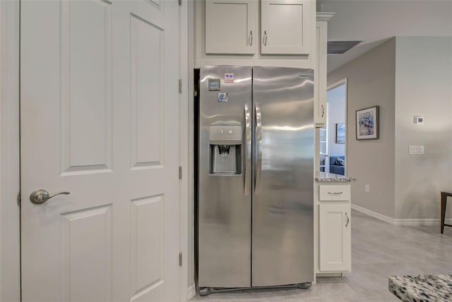 kitchen with light stone countertops, light tile patterned floors, white cabinets, and stainless steel refrigerator with ice dispenser