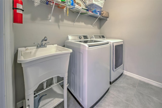 laundry room with sink, light tile patterned floors, and washer and dryer