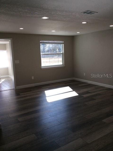 unfurnished room featuring a textured ceiling and dark wood-type flooring