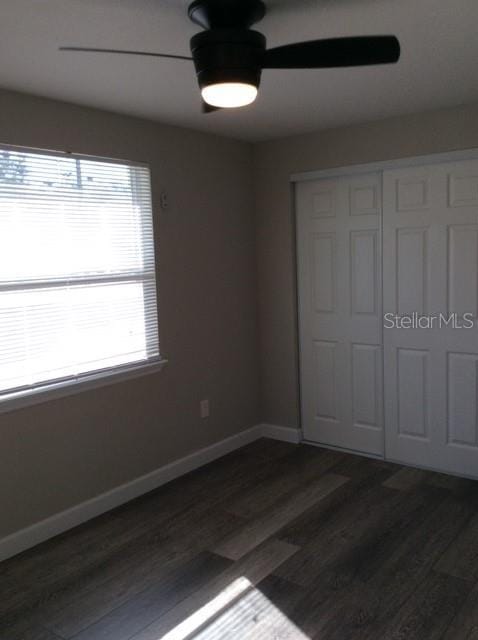 unfurnished bedroom featuring dark hardwood / wood-style floors, a closet, and ceiling fan