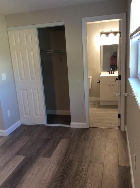 unfurnished bedroom with a closet, dark hardwood / wood-style flooring, ensuite bathroom, and sink