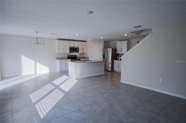 kitchen with white cabinetry, sink, stainless steel appliances, pendant lighting, and a center island with sink