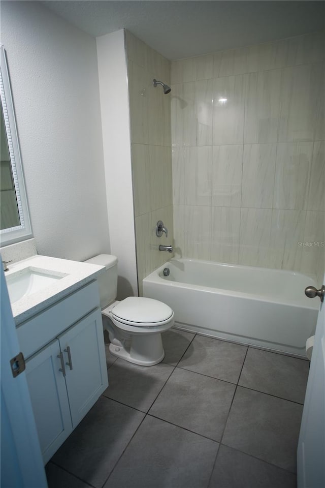 full bathroom with tiled shower / bath, tile patterned flooring, vanity, and toilet