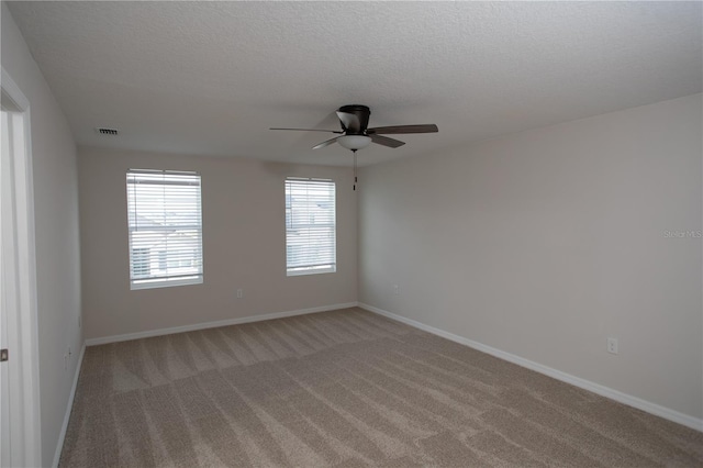 spare room with light carpet, ceiling fan, and a textured ceiling