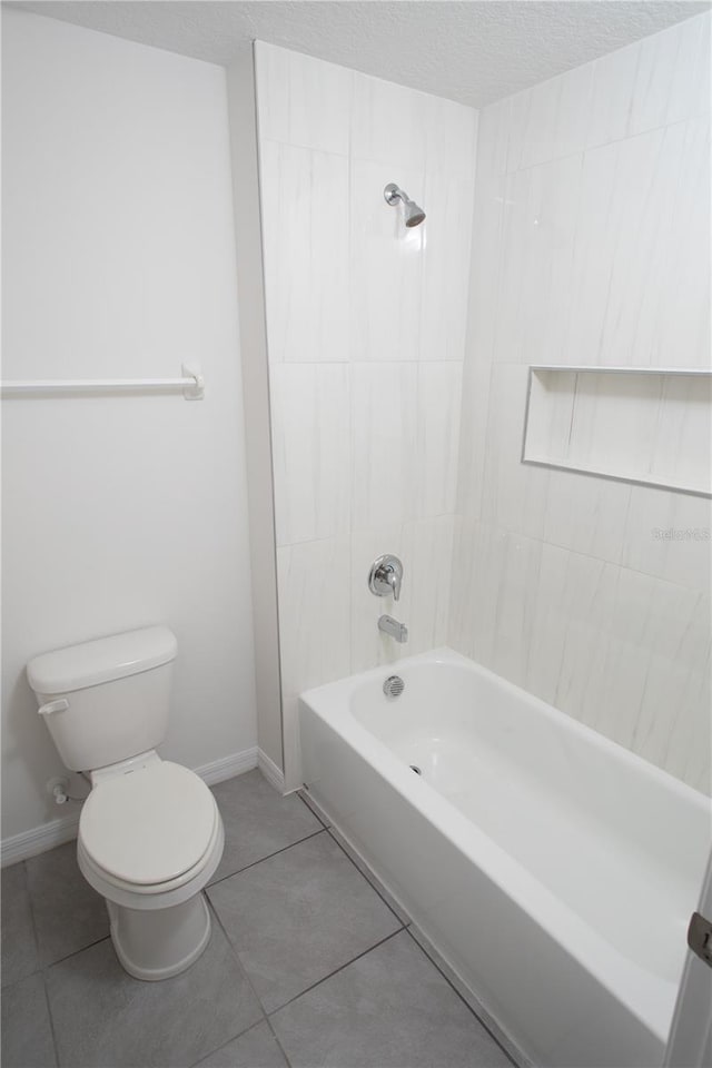 bathroom featuring tile patterned flooring, toilet, and tiled shower / bath