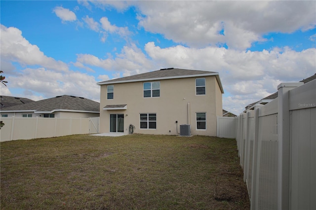 back of house with central air condition unit and a yard