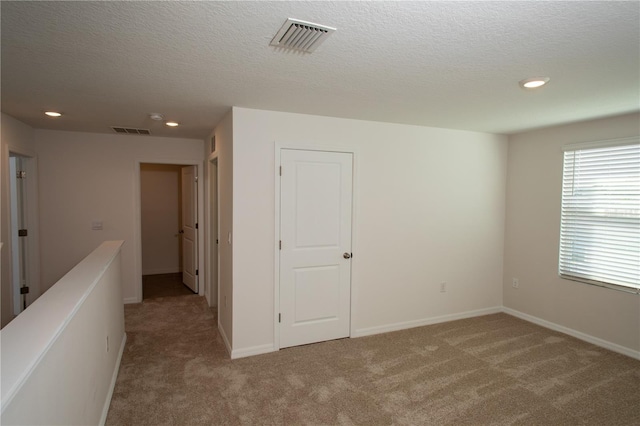 carpeted spare room featuring a textured ceiling