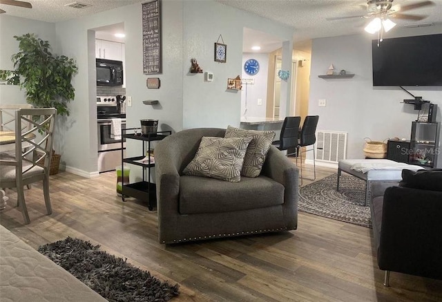 living room with a textured ceiling, hardwood / wood-style flooring, and ceiling fan