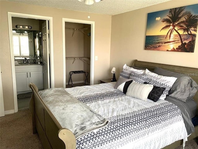 bedroom featuring a spacious closet, a textured ceiling, connected bathroom, carpet floors, and a closet