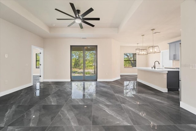 interior space with a raised ceiling, ceiling fan, and sink