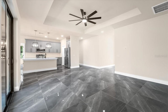 unfurnished living room with a raised ceiling and ceiling fan