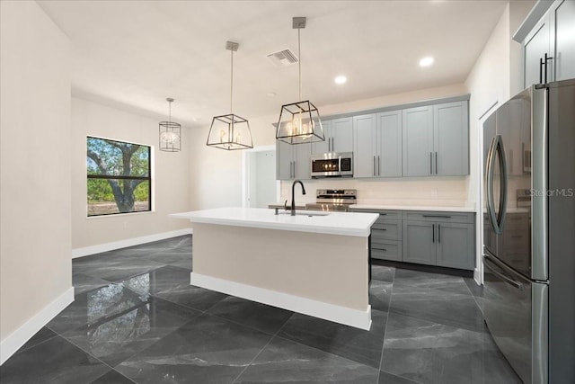 kitchen with pendant lighting, gray cabinetry, a kitchen island with sink, sink, and stainless steel appliances