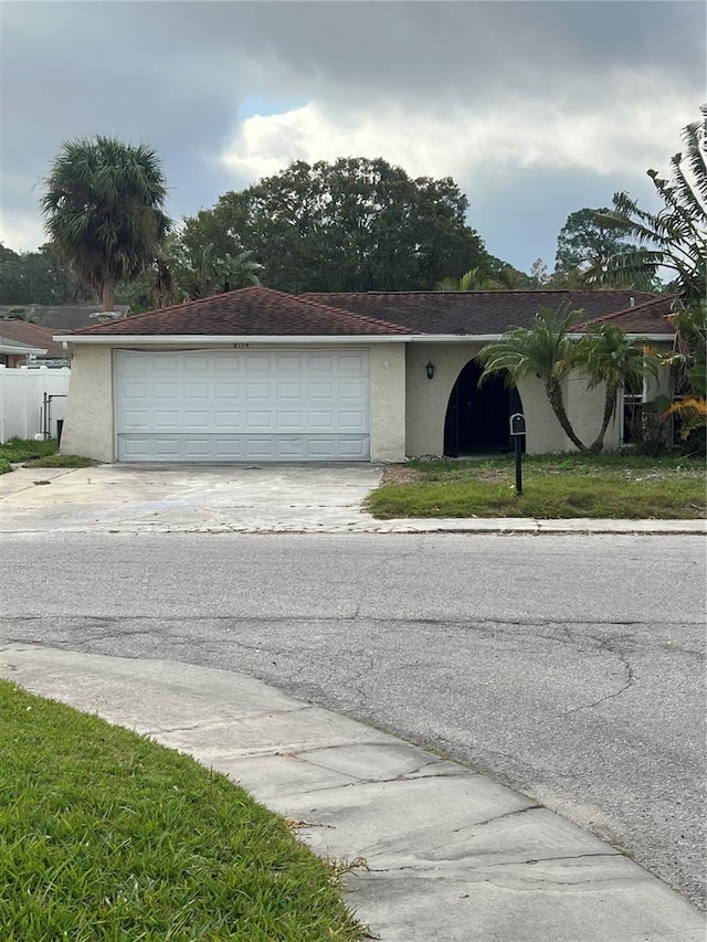 ranch-style house featuring a garage and a front lawn