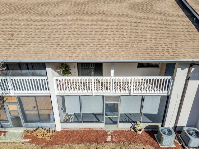 rear view of property featuring a shingled roof, a balcony, and stucco siding