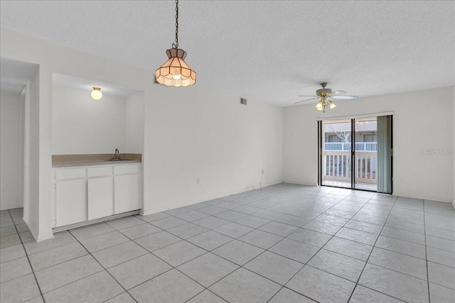 spare room with ceiling fan, a textured ceiling, light tile patterned flooring, a sink, and visible vents