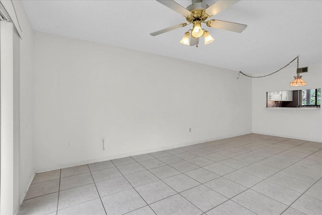 spare room featuring light tile patterned floors, visible vents, and a ceiling fan