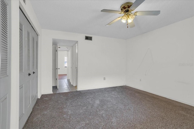 unfurnished bedroom featuring light colored carpet, ceiling fan, visible vents, and a textured ceiling