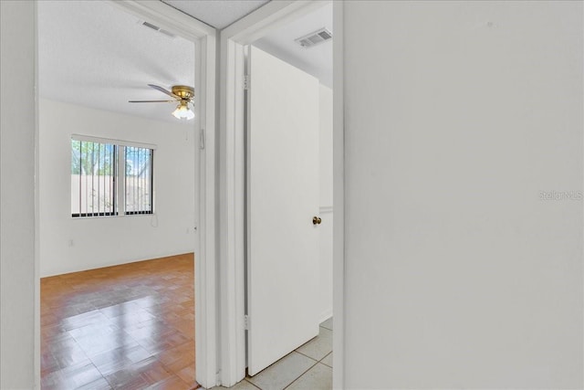 hallway featuring visible vents and a textured ceiling