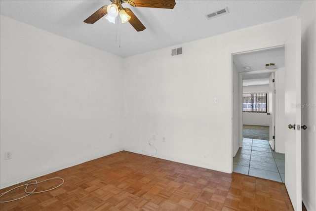 spare room featuring ceiling fan, visible vents, and a textured ceiling