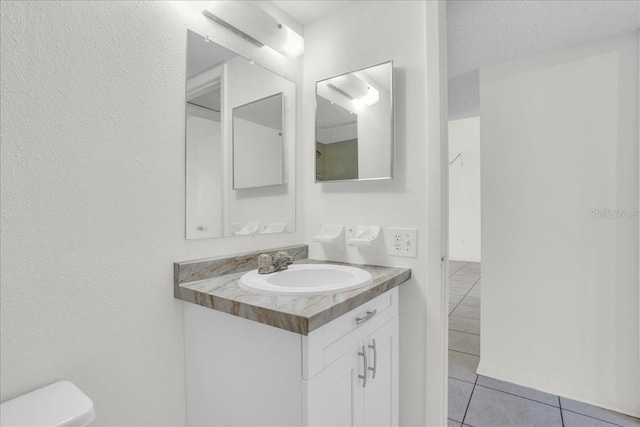 half bath with toilet, tile patterned floors, and vanity