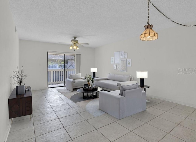 living area featuring a textured ceiling, light tile patterned floors, a ceiling fan, and baseboards