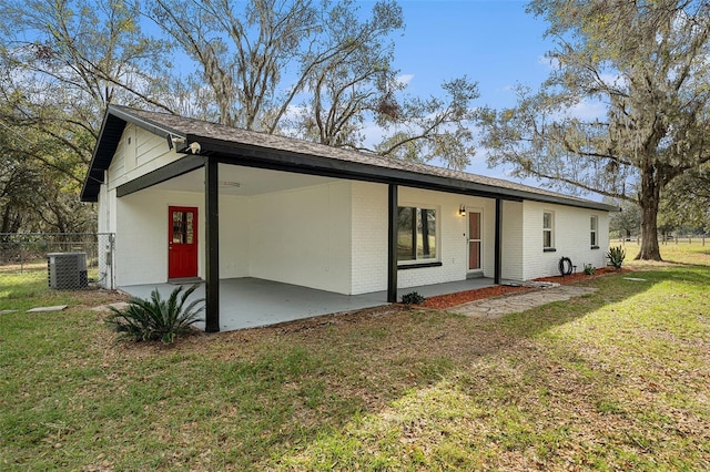 rear view of property with central air condition unit, a patio area, and a lawn