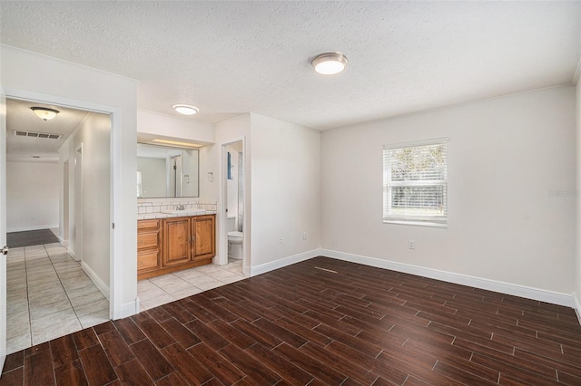 spare room with sink, a textured ceiling, and hardwood / wood-style flooring