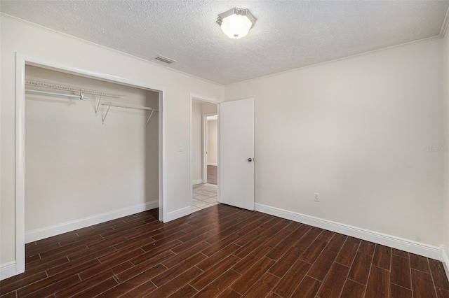 unfurnished bedroom featuring dark hardwood / wood-style flooring, a textured ceiling, and a closet