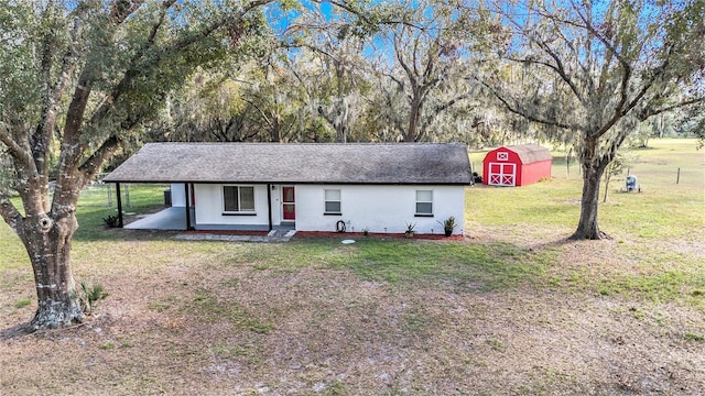 ranch-style house featuring a front yard and a storage unit