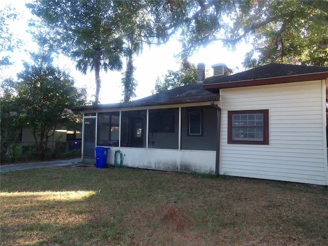 rear view of house featuring a sunroom and a lawn