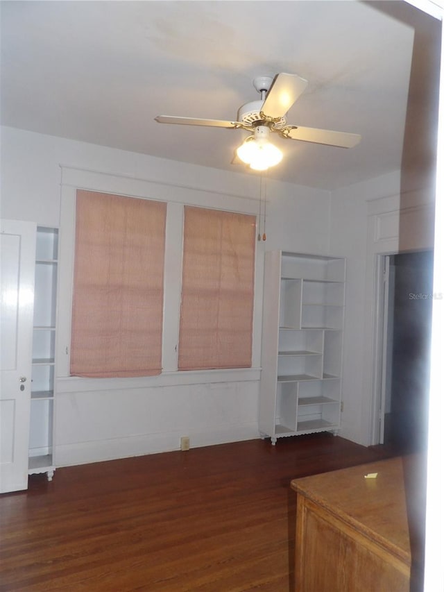 unfurnished living room featuring ceiling fan and dark wood-type flooring