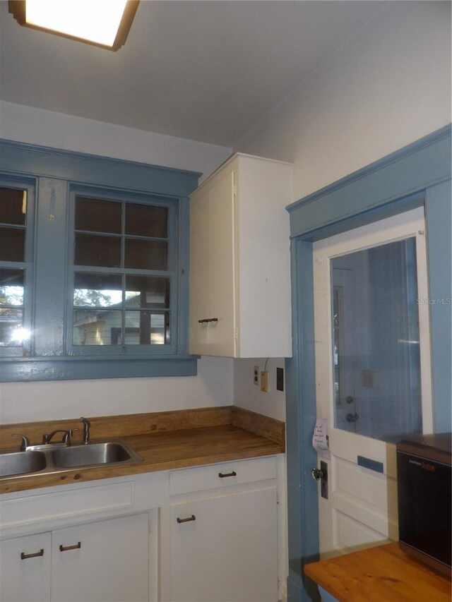 kitchen featuring wood counters, white cabinetry, and sink