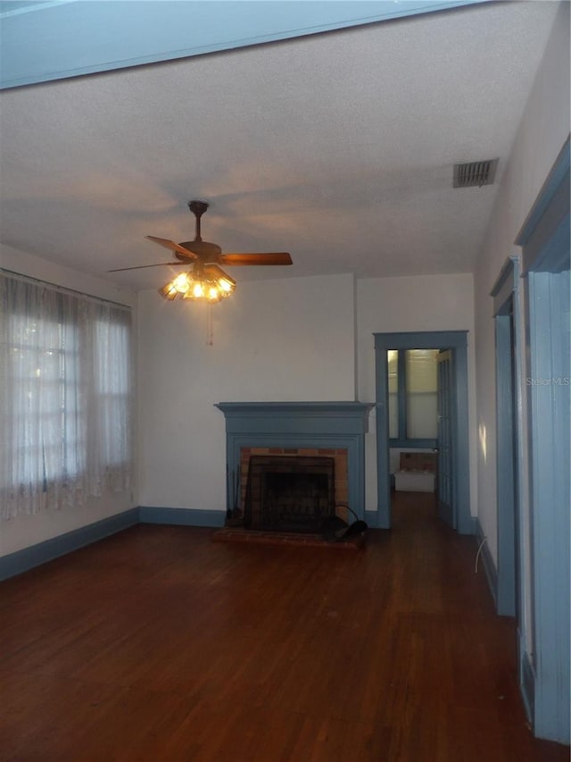 unfurnished living room featuring a fireplace, ceiling fan, dark hardwood / wood-style flooring, and a textured ceiling