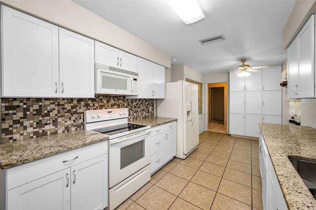 kitchen with backsplash, light tile patterned floors, white cabinets, and white appliances