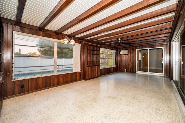 interior space featuring beam ceiling, ceiling fan with notable chandelier, a wall mounted AC, and wood walls