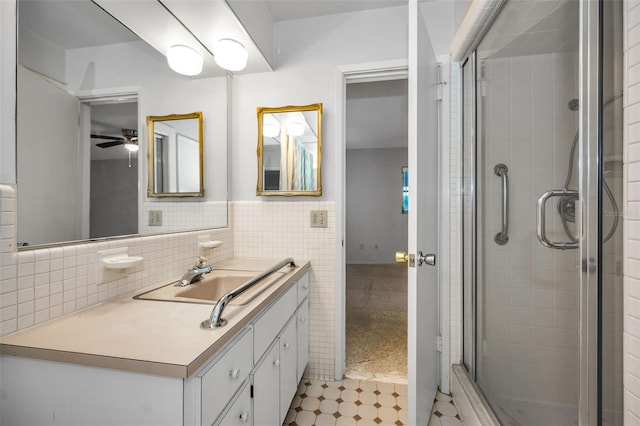 bathroom with vanity, ceiling fan, an enclosed shower, and tile walls