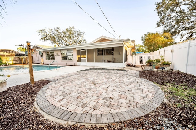 rear view of property with a fenced in pool, a patio area, and a sunroom