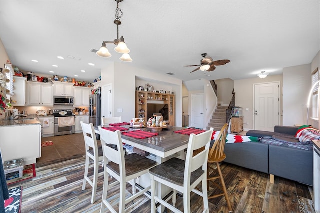 dining room with a textured ceiling, ceiling fan with notable chandelier, sink, and dark wood-type flooring