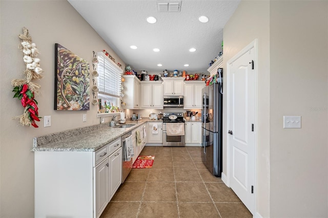 kitchen featuring white cabinets, appliances with stainless steel finishes, light stone countertops, and sink