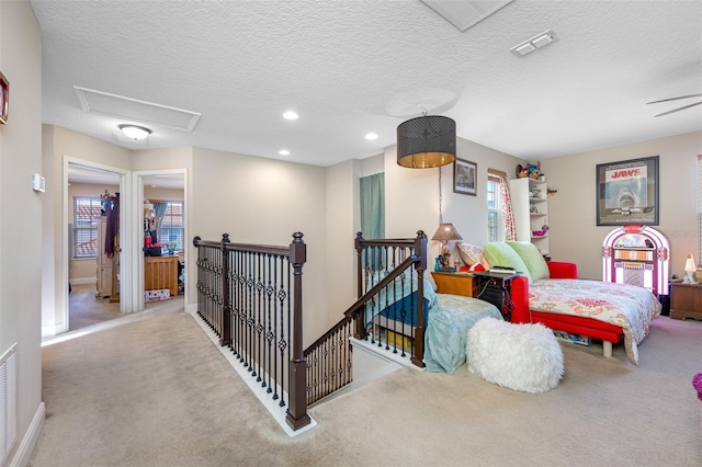 hall with light colored carpet and a textured ceiling