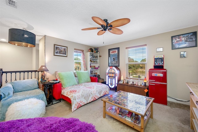 bedroom featuring a textured ceiling, light colored carpet, and ceiling fan