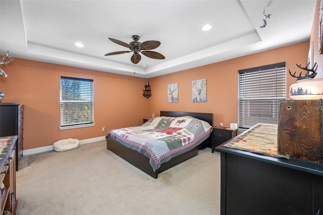 carpeted bedroom featuring a tray ceiling and ceiling fan