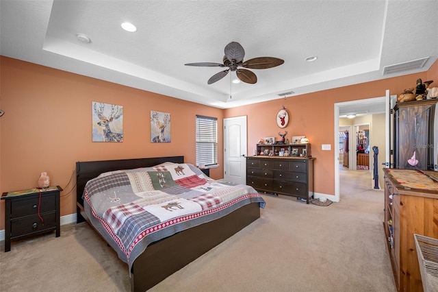 carpeted bedroom with ceiling fan, a textured ceiling, and a tray ceiling