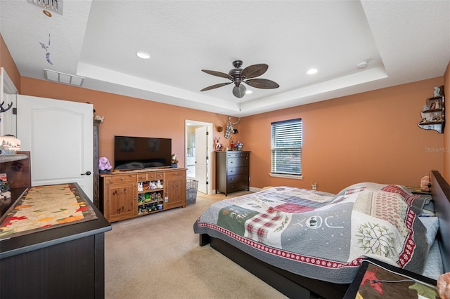 carpeted bedroom featuring a textured ceiling, a tray ceiling, and ceiling fan