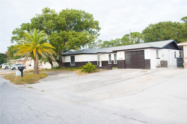 ranch-style home with a garage and central AC unit