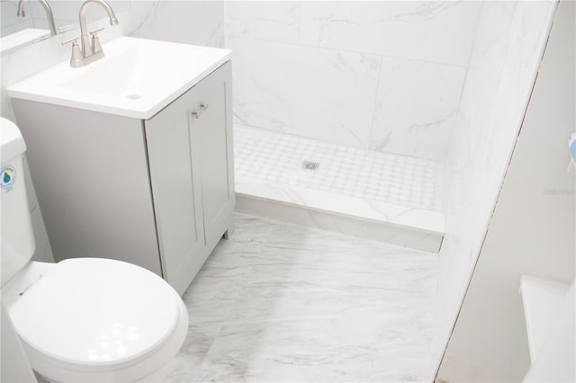 bathroom with toilet, vanity, and tiled shower