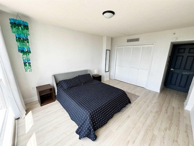 bedroom featuring a closet, a textured ceiling, and light wood-type flooring