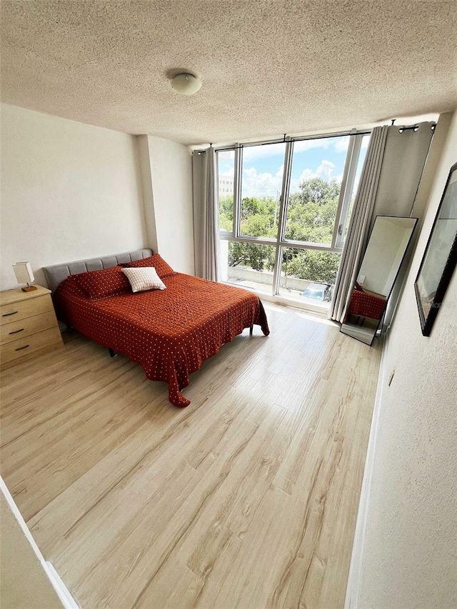 bedroom featuring a wall of windows, a textured ceiling, and hardwood / wood-style flooring