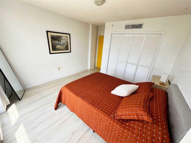 bedroom featuring a textured ceiling, light hardwood / wood-style floors, and a closet